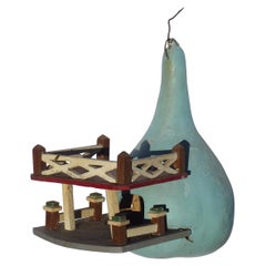 A nicely painted birdhouse built of wood set into a gourd. good detail and look.