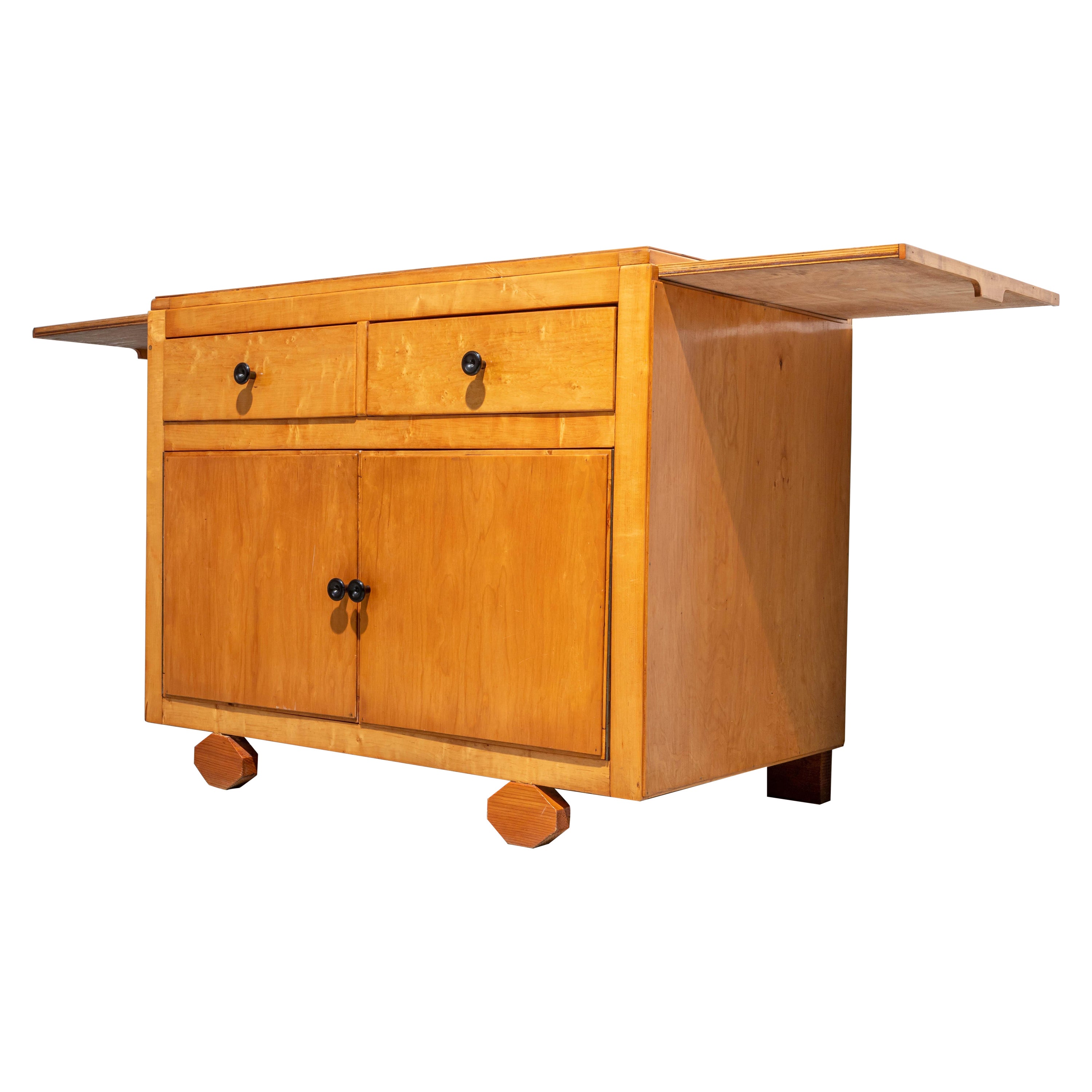 Deliziosa credenza artigianale a due ante con piedi a diamante. Un bel legno biondo quasi giallo che si è mantenuto molto bene nel corso degli anni. Molto pratico anche grazie alle foglie estraibili che ti permettono di renderlo un po' più grande se