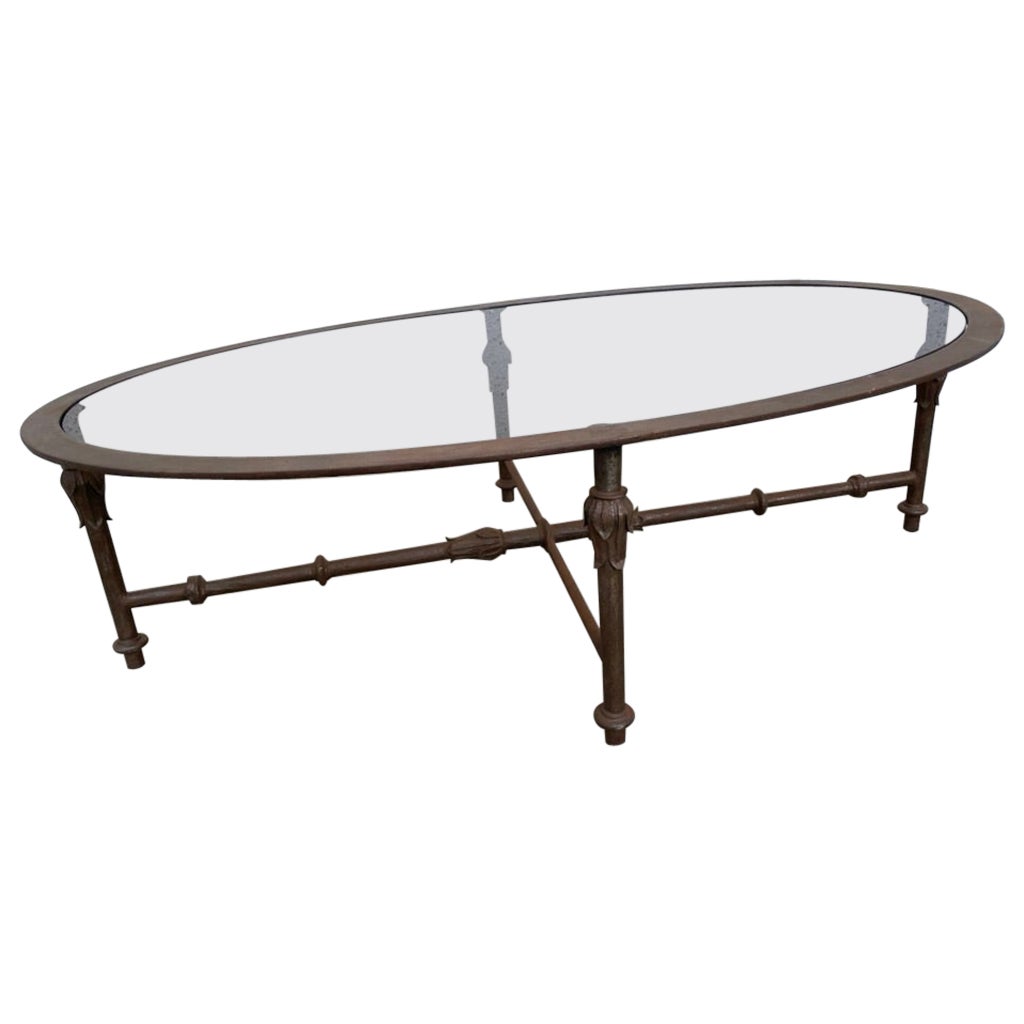 Very interesting and stylish Italian Mid-Century Modern wrought and cast iron oval coffee table. The four legs with acanthus leaf decoration joined by cross stretchers. A successful modern take on the Neoclassical. 
Replaced glass, scratch