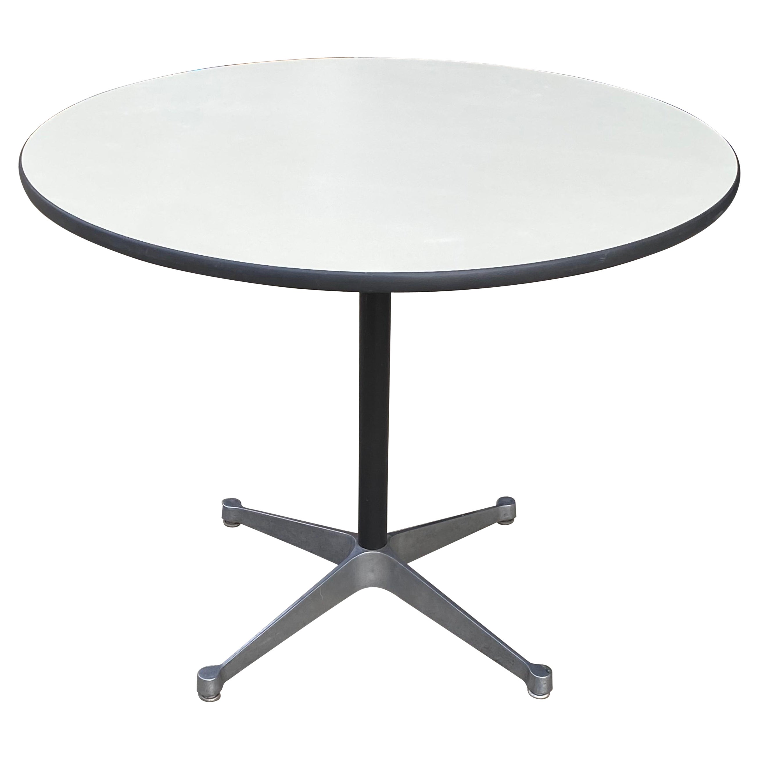 Classic and elegant Eames dining table for Herman Miller. White laminate round 36” tabletop with durable banded edge, atop black pole and cast aluminum 4 leg base. In good original condition. Signed with two Herman Miller labels, and stamped with