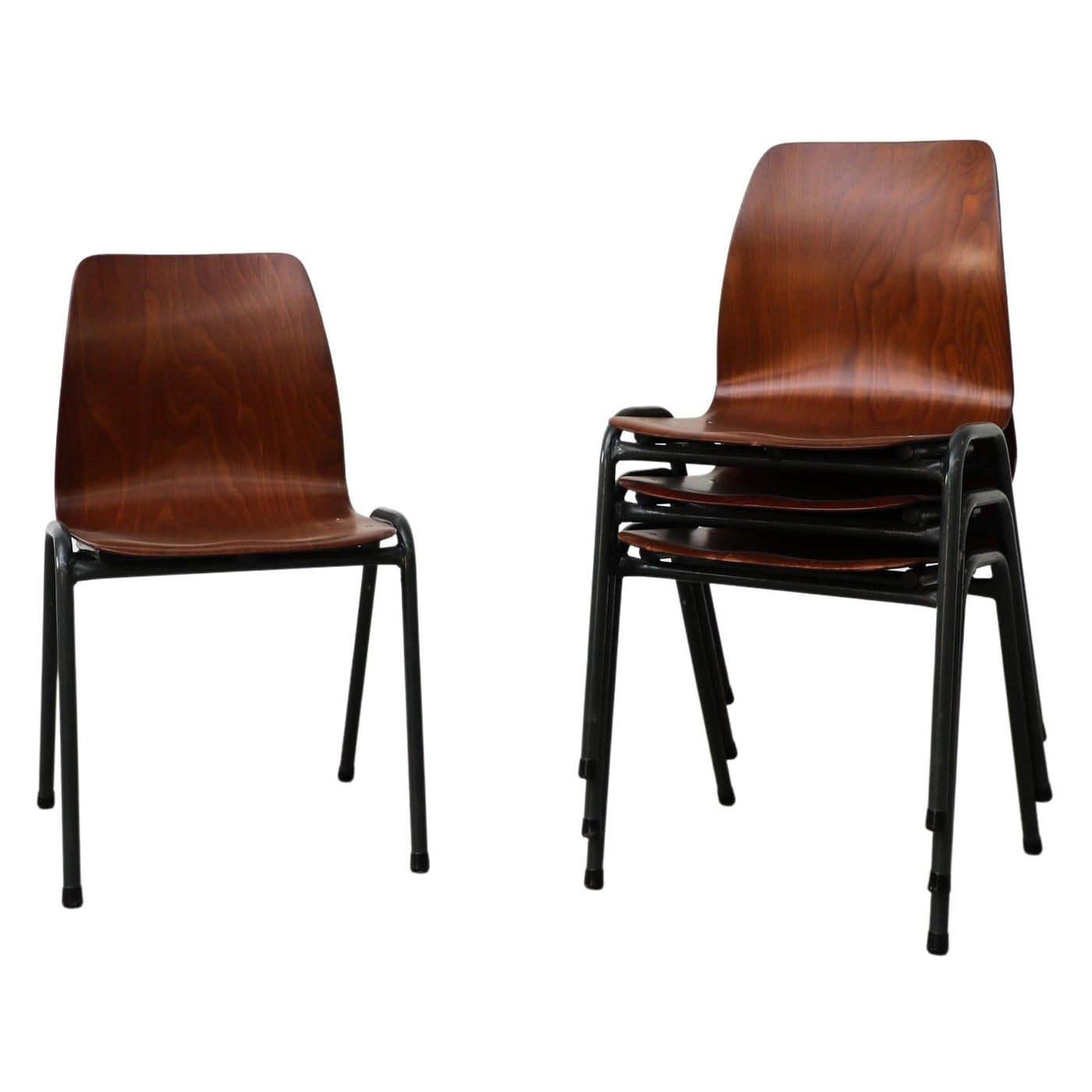 Ensemble de quatre chaises empilables industrielles foncées avec sièges simples en coquillage de couleur foncée