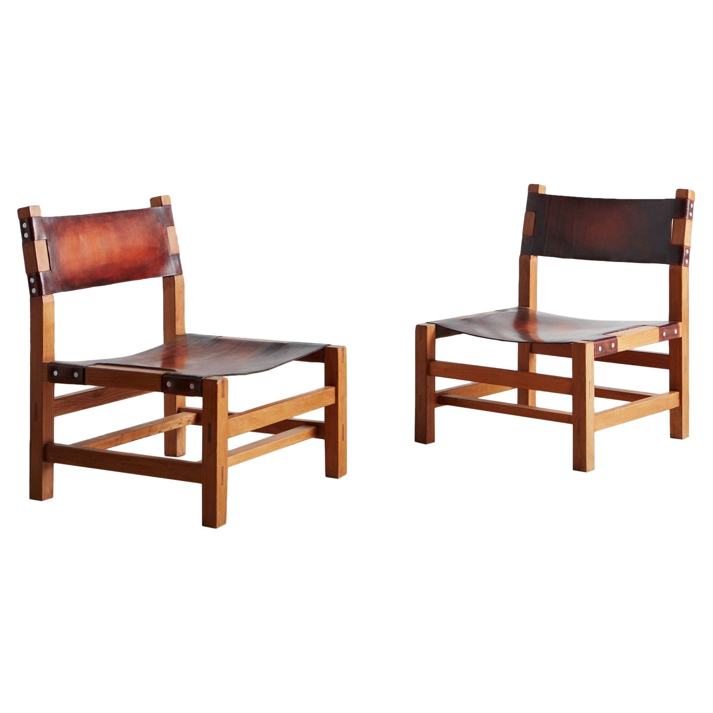 Paire de chaises longues de cheminée en bois d'orme et cuir attribuées à la Maison Regain 