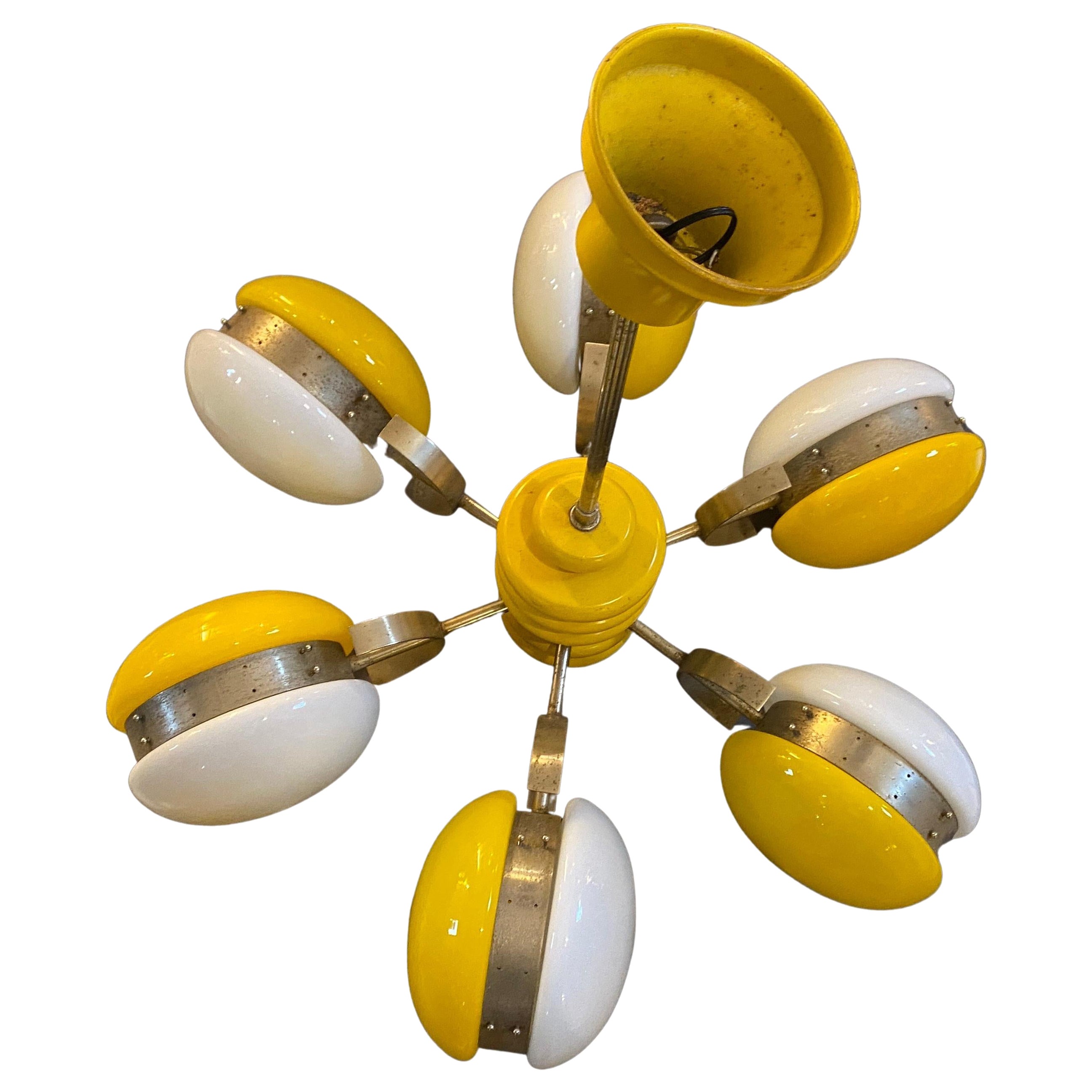 An amazing Space Age Chandelier designed and manufactured in Italy in the Seventies. The white and yellow glasses are in perfect conditions, the yellow painted wood and metal parts are in original conditions, it works both 110-240 volts and it needs