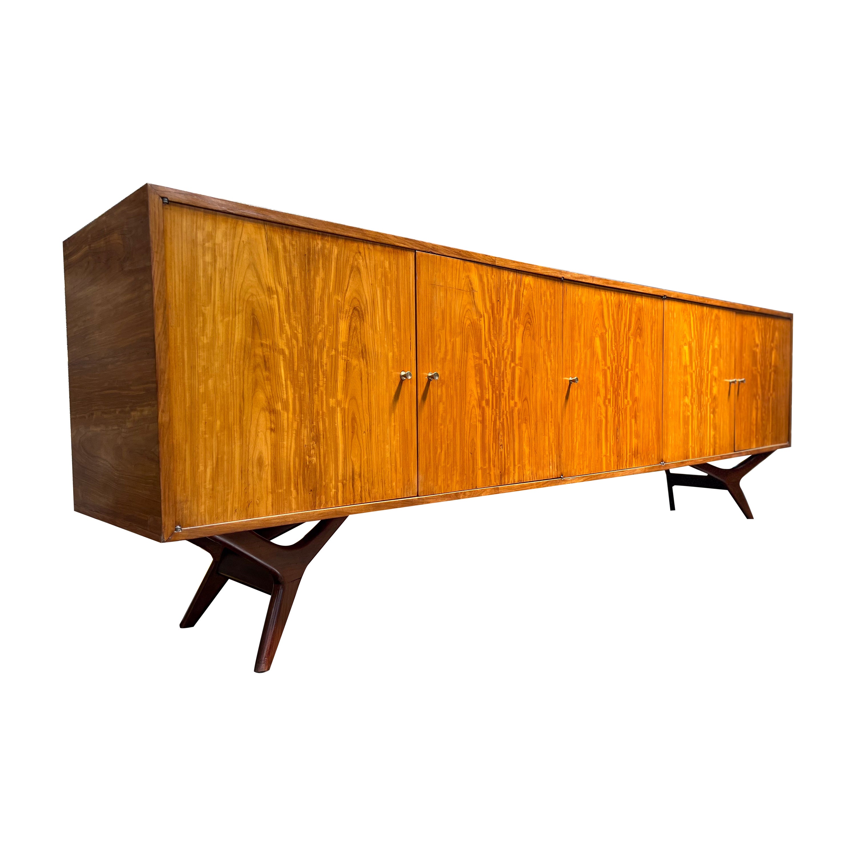 Available today, this magnificent Mid-Century Modern Credenza in Caviuna Hardwood designed by Forma Moveis in Brazil during the sixties decade is absolutely gorgeous!

The piece is entirely made of Caviuna hardwood and features five doors with brass