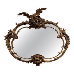 George III Style Heavily Carved Rococo Oval Giltwood Mirror with Eagle Crest