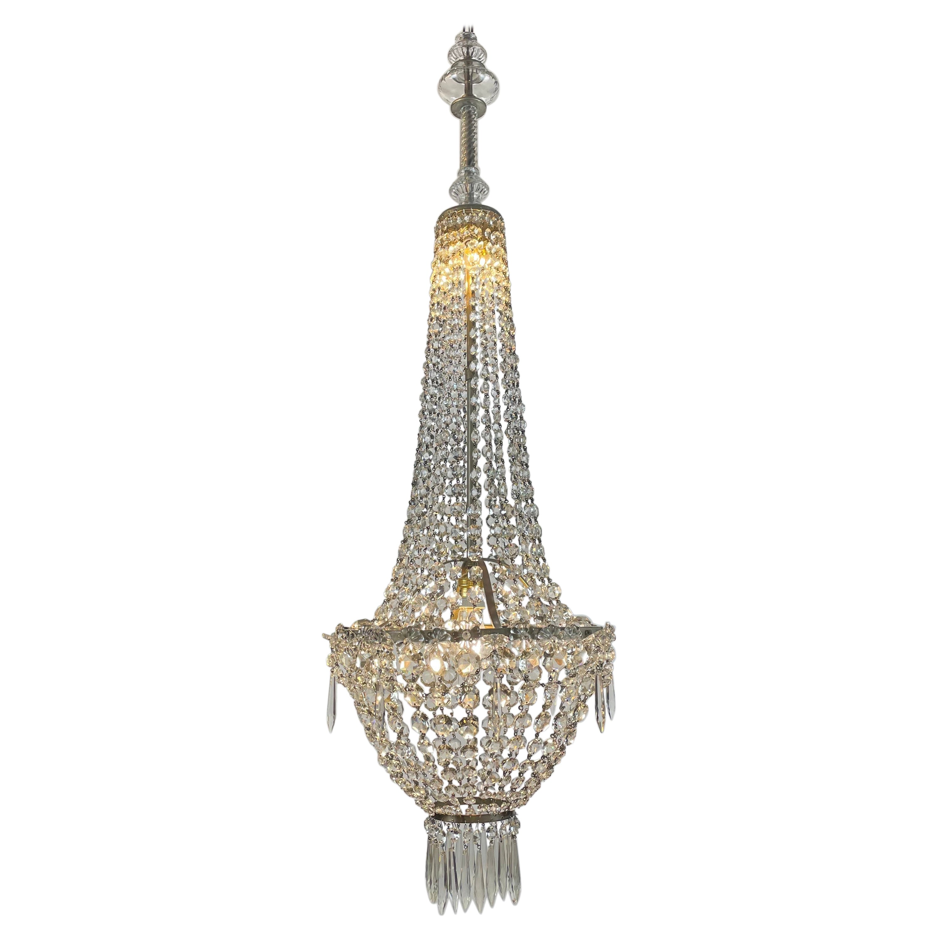 An early-20th century Empire style beaded crystal basket chandelier with a high central stem, a classical circular crystal structure, three E14 lights inside, in the upper section, and one single E27 light bulb in the lower part, at the bottom,