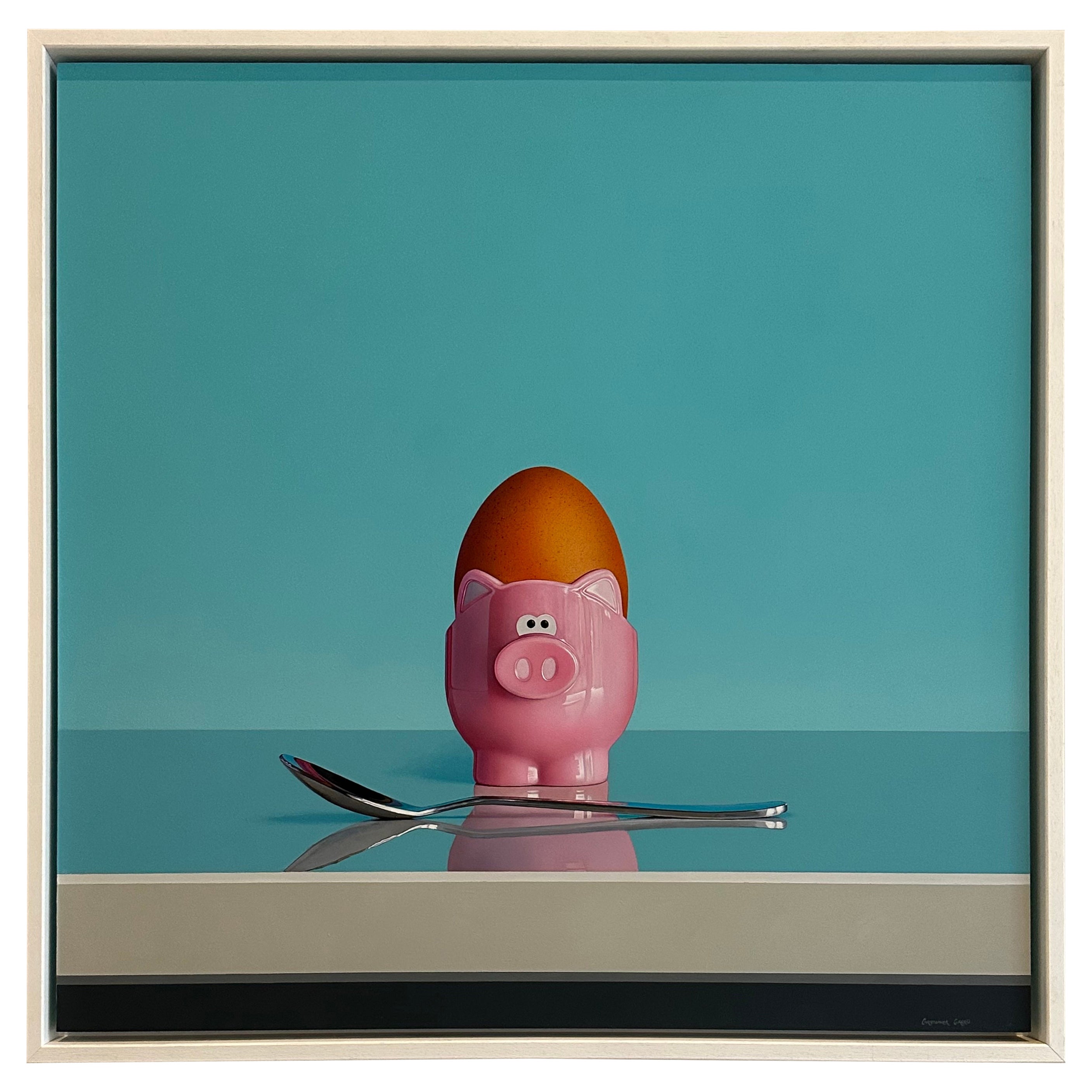 A square painting that will bring an immediate smile to your face of an egg cup designed in the shape of a pink pig with an egg inside and a silver polished spoon placed in front. The pig is from the Joie Egg Cup range of products. I have been