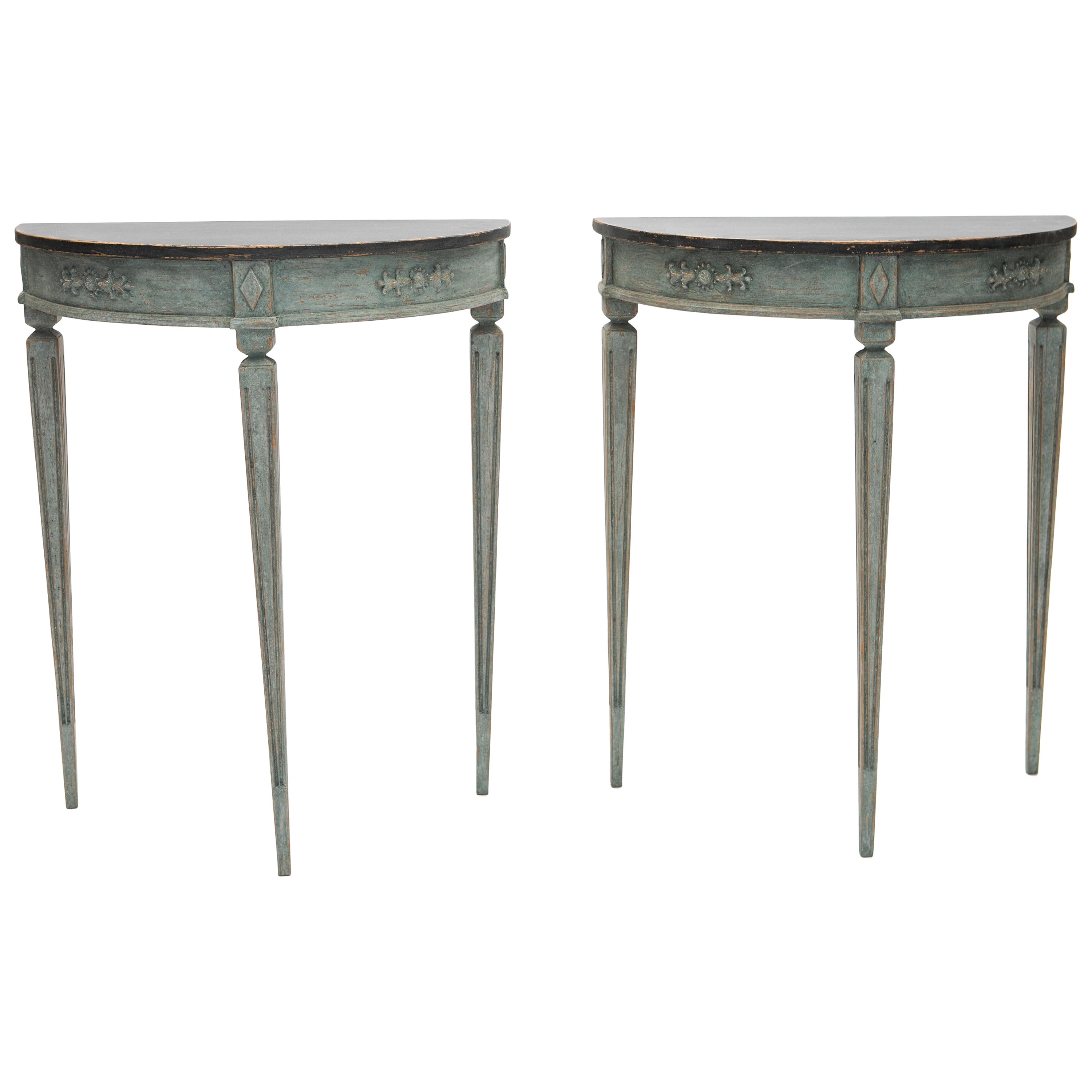 Elegant pair of demilune console tables in Gustavian Style.
Gray marbled table top with edge profile, frame with flower and foliage ornamentation.

Lower part blue painted, tapered legs with flutes.
Sweden approx. 1900.