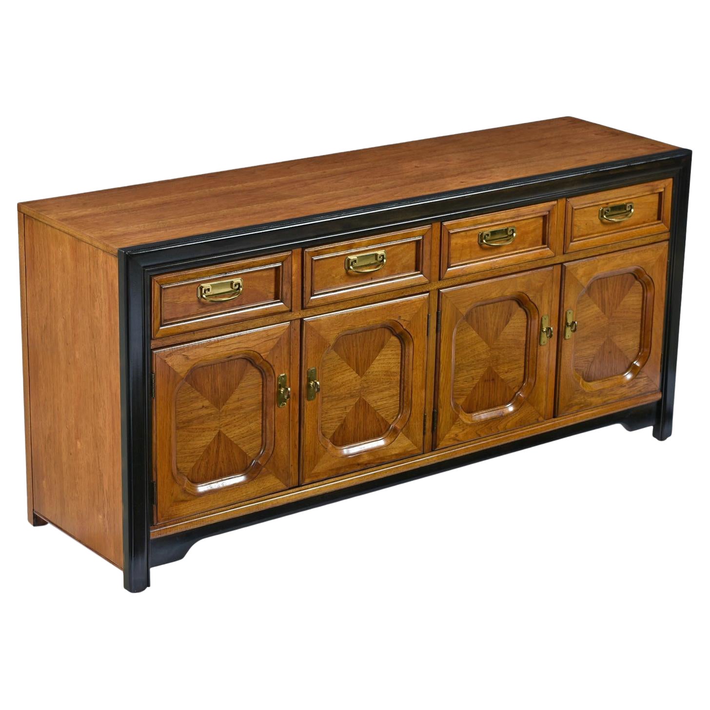 Dorothy Draper style campaign credenza made by esteemed US furniture maker Thomasville circa 1970s. Old growth flaxen flared grain fruitwood (most likely pecan) from top to bottom are the hallmarks of the Embassy line. Black lacquer accents and