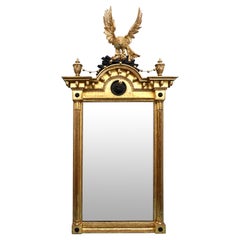 Fino espejo de madera dorada de la Regencia con cresta de águila tallada y remates de máscara de león