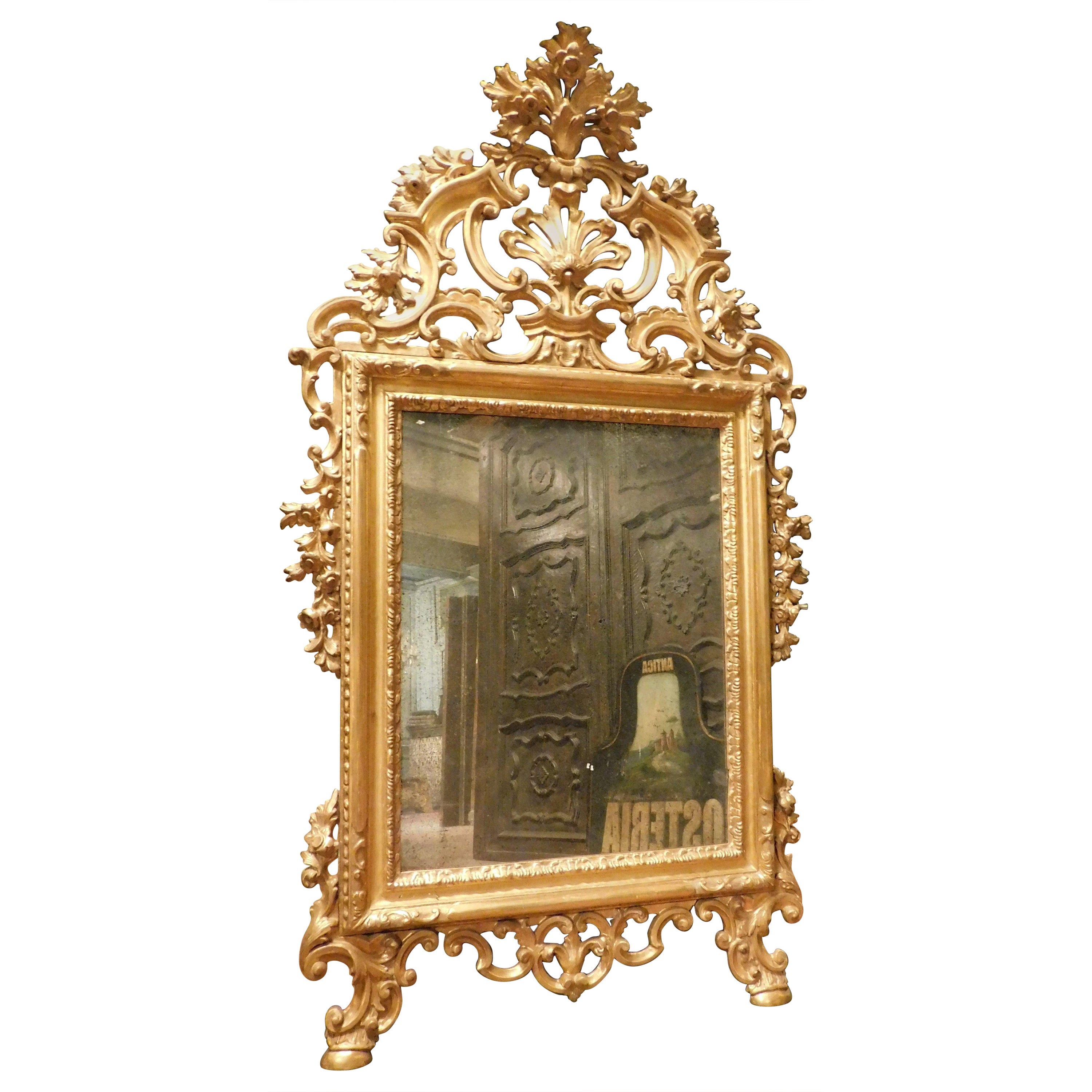 Miroir en bois doré, richement perforé de volutes en frise, à motifs floraux et feuillus, 800
