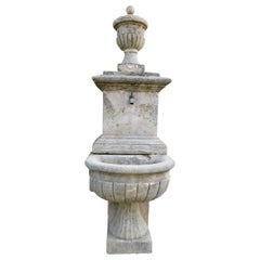 Fountain in gray stone, with spout and applied to the wall, Italy
