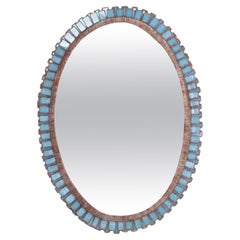 Un miroir ovale en résine dorée et verre bleu, à la manière de Line Vautrin. 