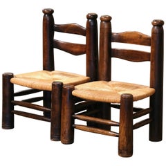 Paire de chaises basses du début du 20e siècle en noyer sculpté et assise en jonc.