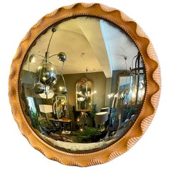 Un grand miroir convexe vieilli dans un cadre en chêne sculpté 