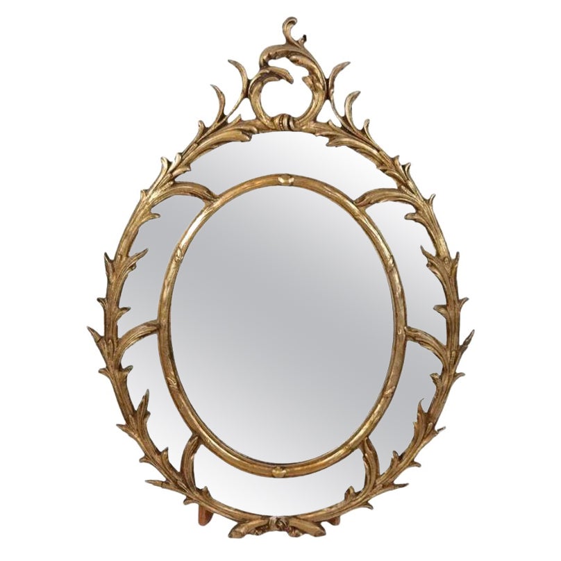 Miroir ovale en bois doré avec motif de volutes en vente