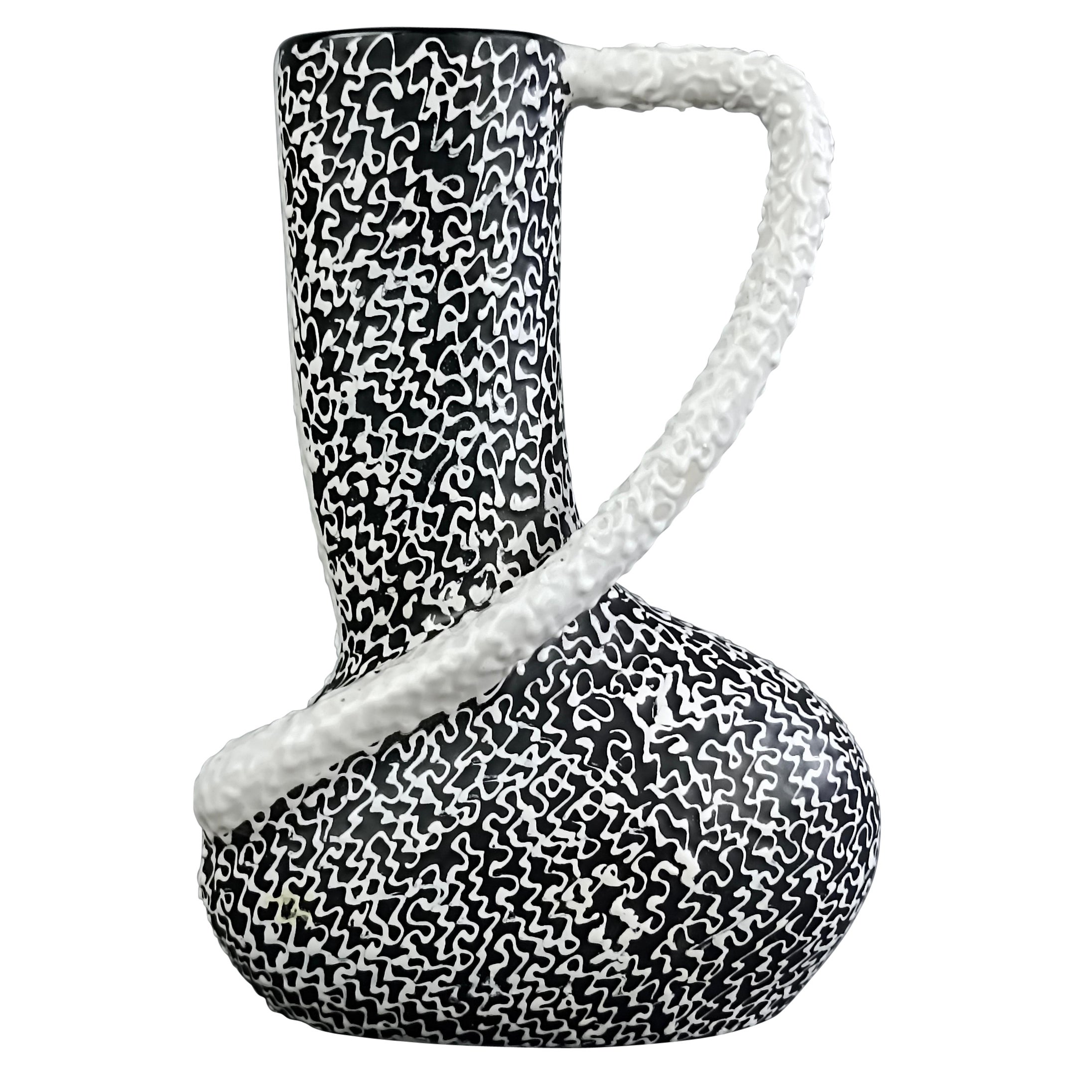 Elegant asymmetrical 1950s Italian Modernist style ceramic vase. The vase has a rather original shape, frontally it is black, as well as internally, while the back is white.
Equally particular and interesting is the shape of the handle applied