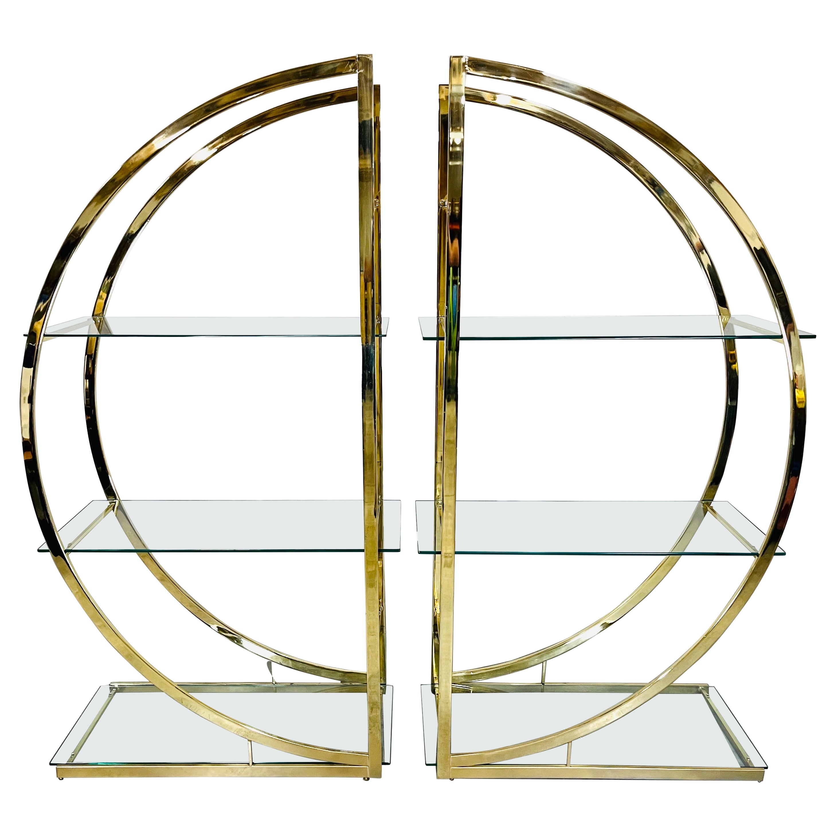 An elegant double half circle brass etagere having 6 tempered glass shelves with an additional 2 tempered glass bridge shelves for a wider setup. 
Manufactured by Design Institute of American in the manner of Milo Baughman. 
United States circa