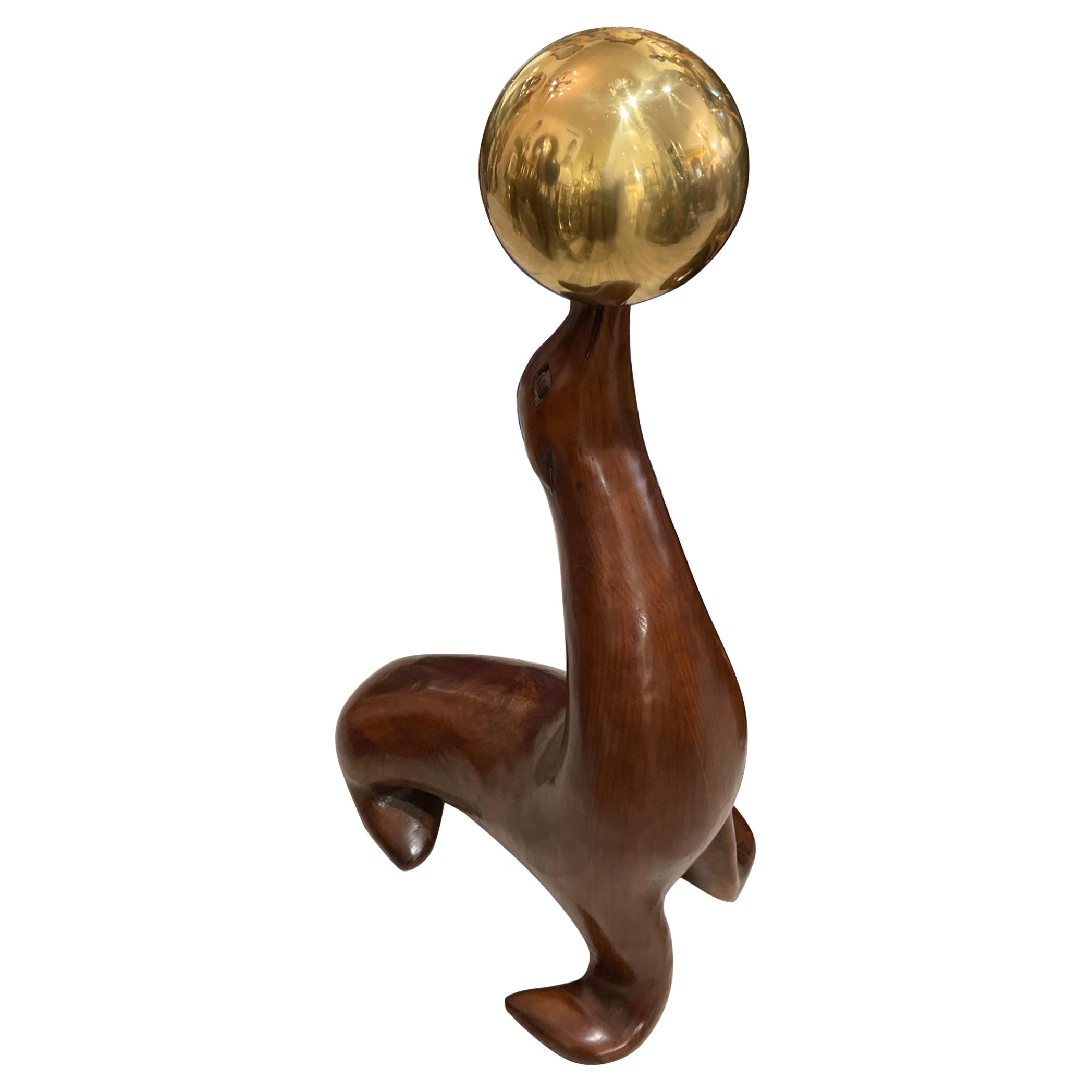 Grande sculpture en bois d'un sceau balançant une boule de laiton