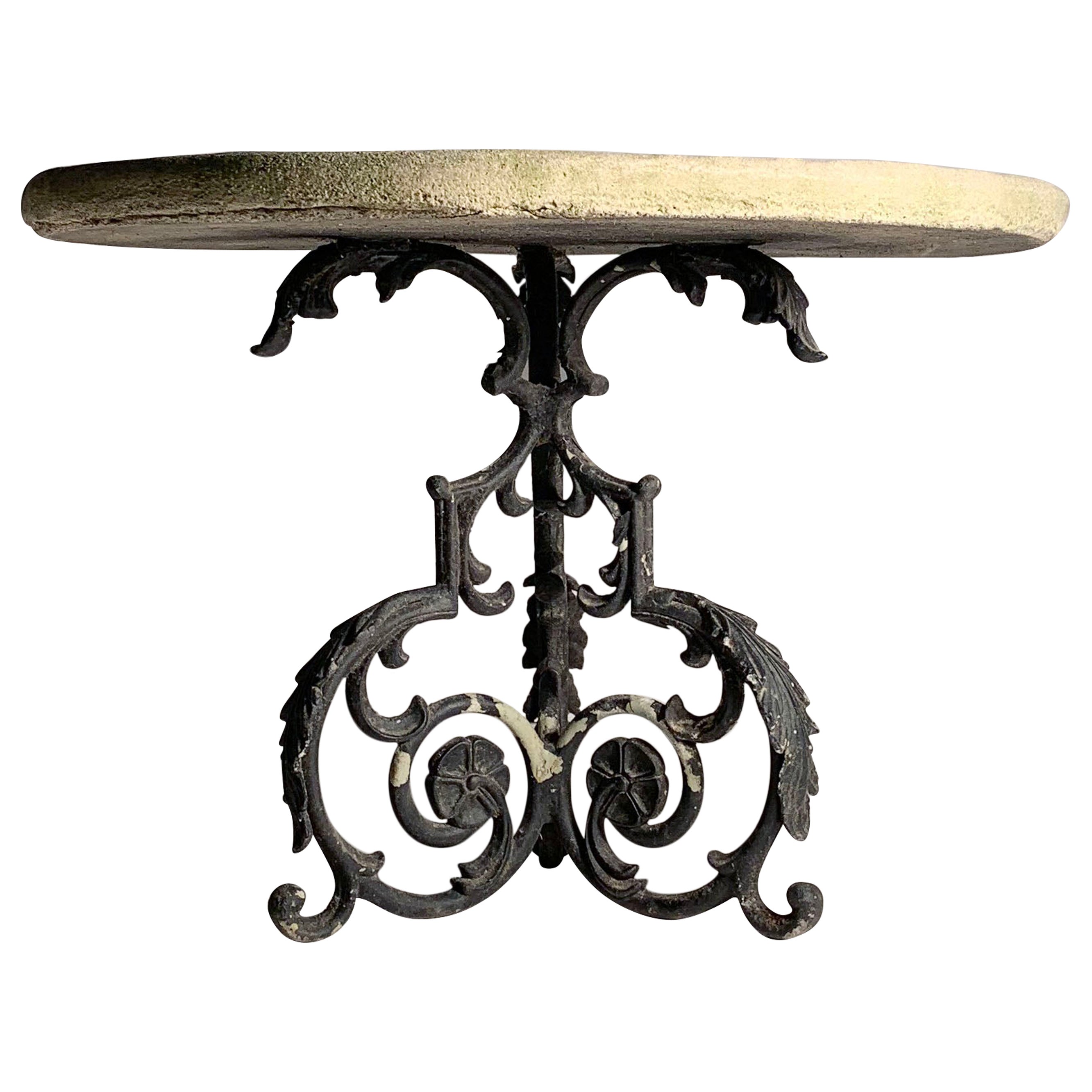 Pequeña mesa de jardín antigua con un elaborado tablero de piedra fundida
