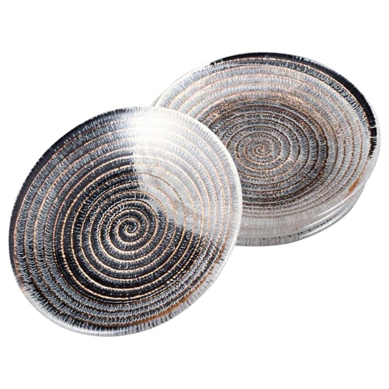 Murano, Italy, four small plates in clear glass with spiral-shaped decoration.