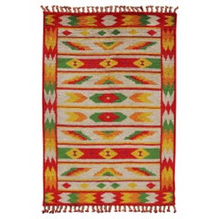 Tapis marocain vintage avec motif tribal sur toute sa surface rouge, vert et jaune