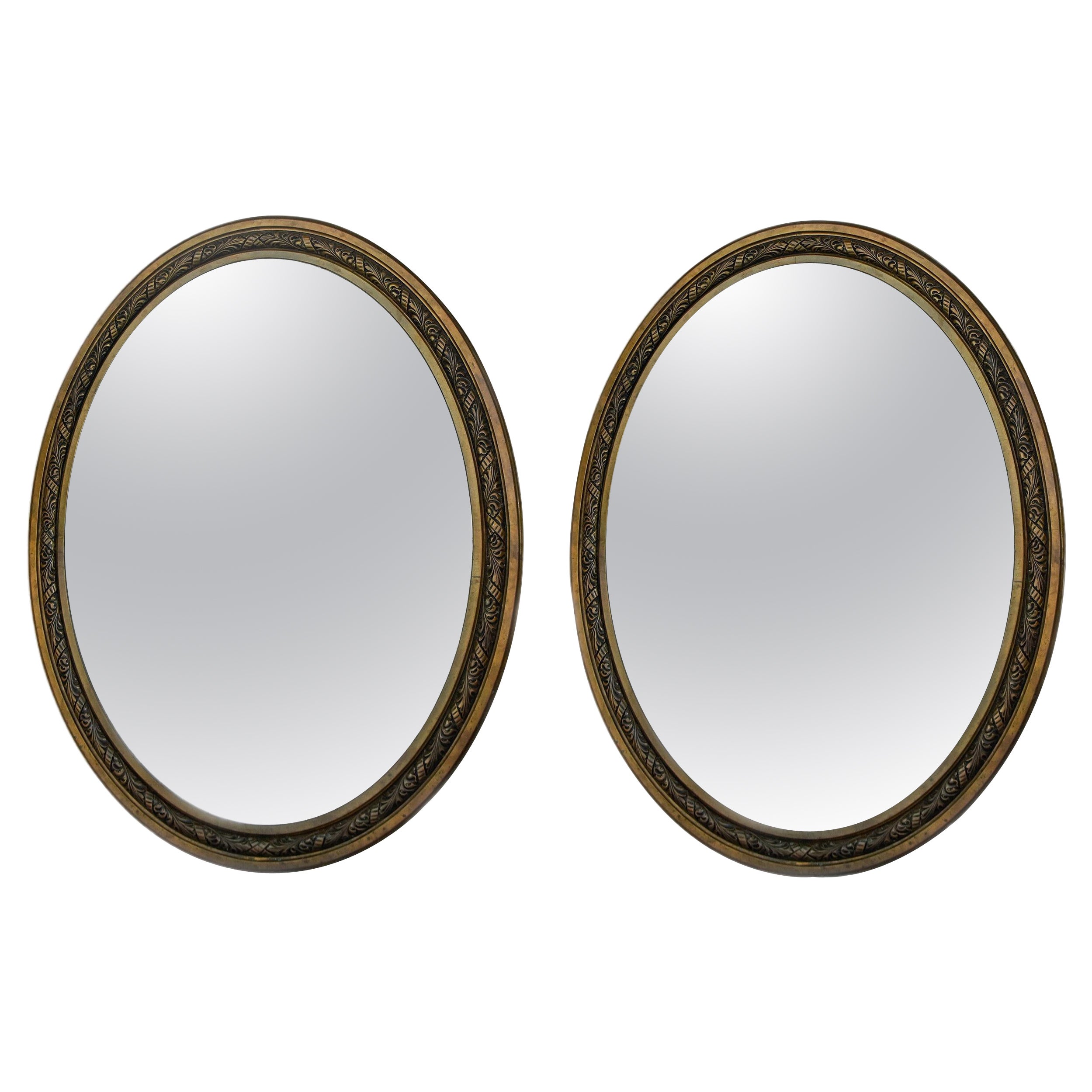 Paire de grands miroirs en bronze à cadre ovale et bords biseautés du début du 20e siècle. 