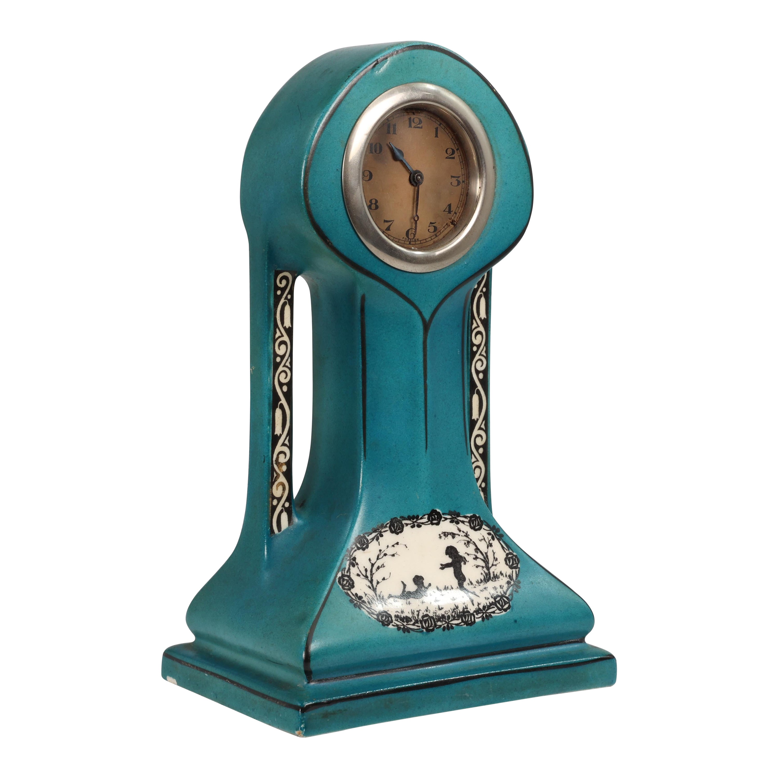 A little turquoise blue dressing table clock decorated with cherubs by a tree. For Sale