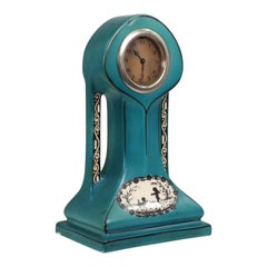 Antique A little turquoise blue dressing table clock decorated with cherubs by a tree.