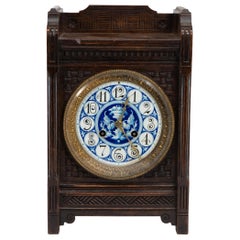 An Anglo-Japanese carved oak mantel clock with hand painted blue floral dial.