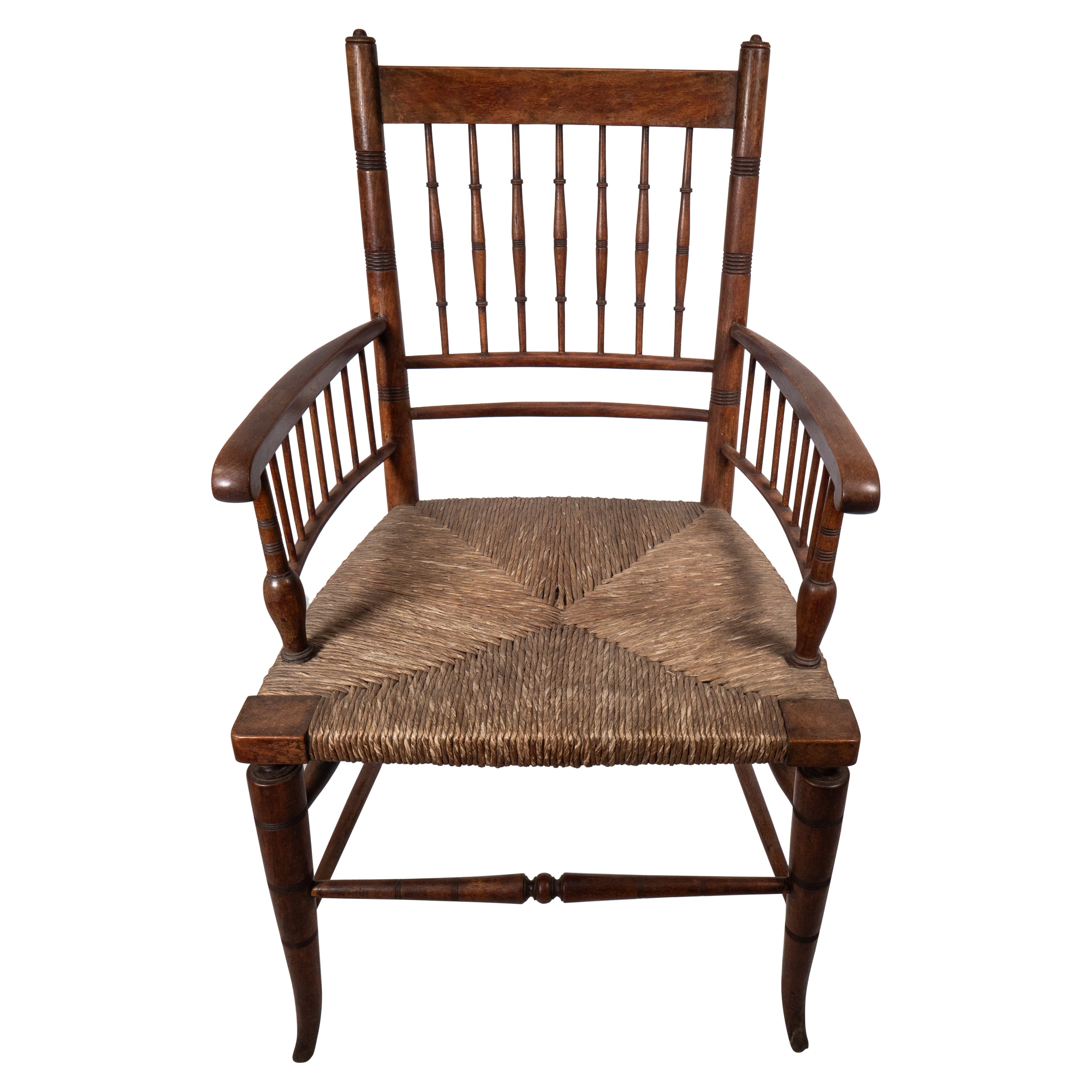Liberty and Co attributed, in the style of a Morris and Co Sussex armchair. An Aesthetic Movement rush seat armchair with incised turnings to the back and below the arms with elegant splayed front legs.
