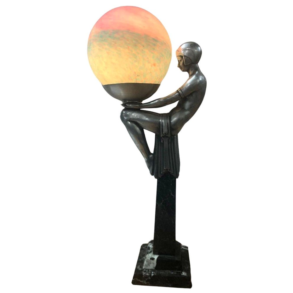 Lampe Art déco représentant une femme tenant un globe coloré en vente