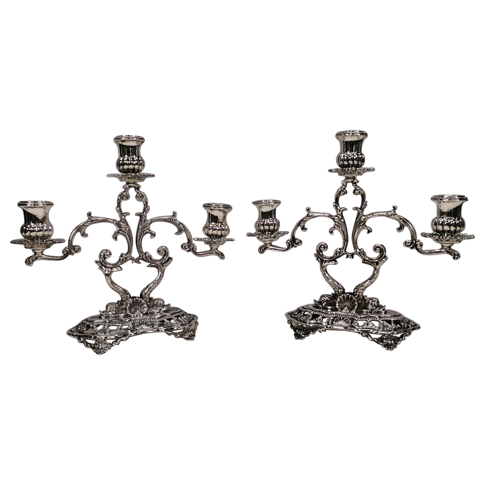 Pair of 3-lights candelabra in Baroque style.
The candlesticks were made with the technique of casting, engraving and chisel completely made by hand.
The oblong-shaped base rests on 4 feet and is shaped and perforated with volute and shell designs,