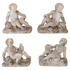 Set of 4 carved limestone fountain putti seated with dolphins