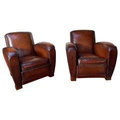 Impressionnante paire de fauteuils club français en cuir, attribuée à Jacques Adnet