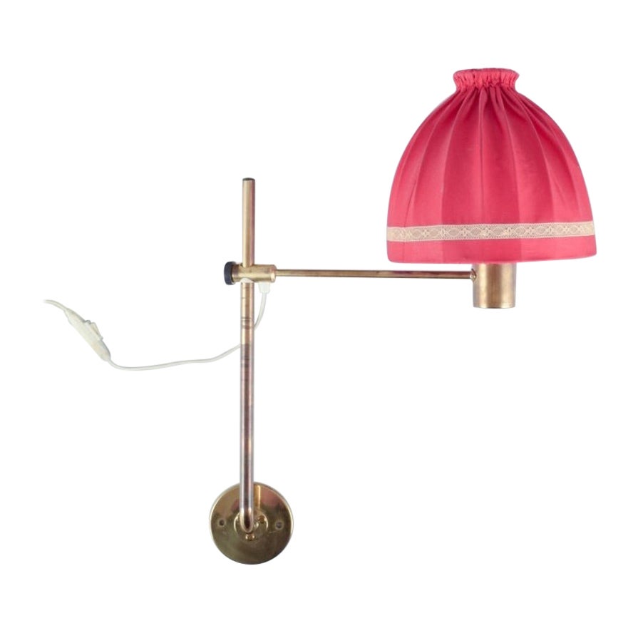 Hans Agne Jakobsson. Wall lamp in brass with a lampshade in red fabric For Sale