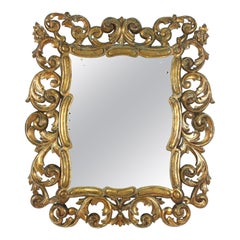 Specchio in legno intagliato e dorato con motivo a volute