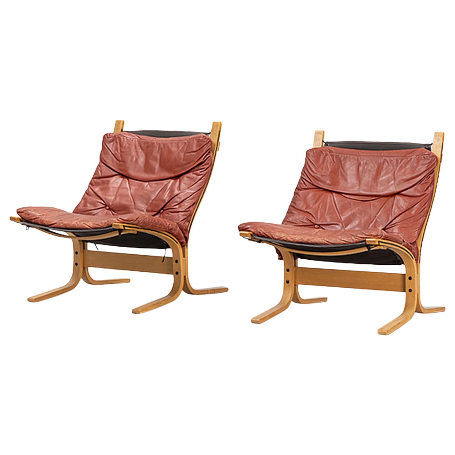 Pair of lowback "Siesta" lounge chairs in rust toned leather + beech