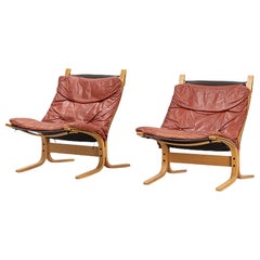 Pair of lowback "Siesta" lounge chairs in rust toned leather + beech
