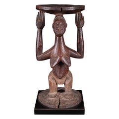 Figura femenina cariátide de pie sobre una base circular, RDC