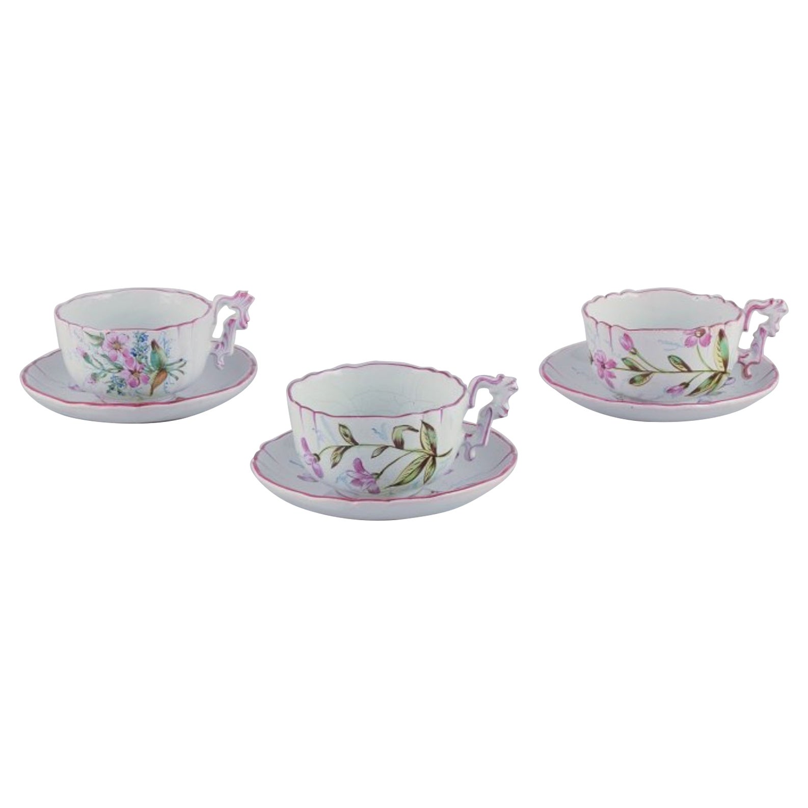 Three hand-painted tea cups and saucers in faience with motifs of flowers. For Sale