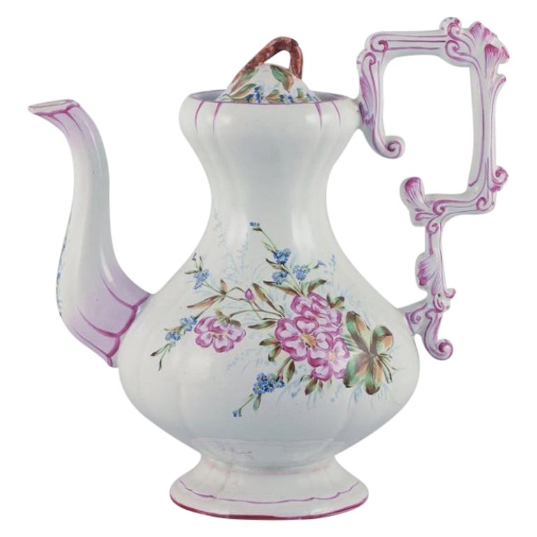 Grande cafetière en faïence avec des motifs de fleurs et d'insectes.