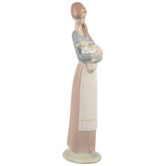 Lladro, Spain. Porcelain figurine of a standing young woman holding a lamb.