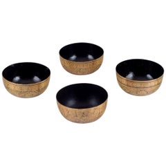 Four Asian bowls made of papier-mâché. Decorated in gold and black.