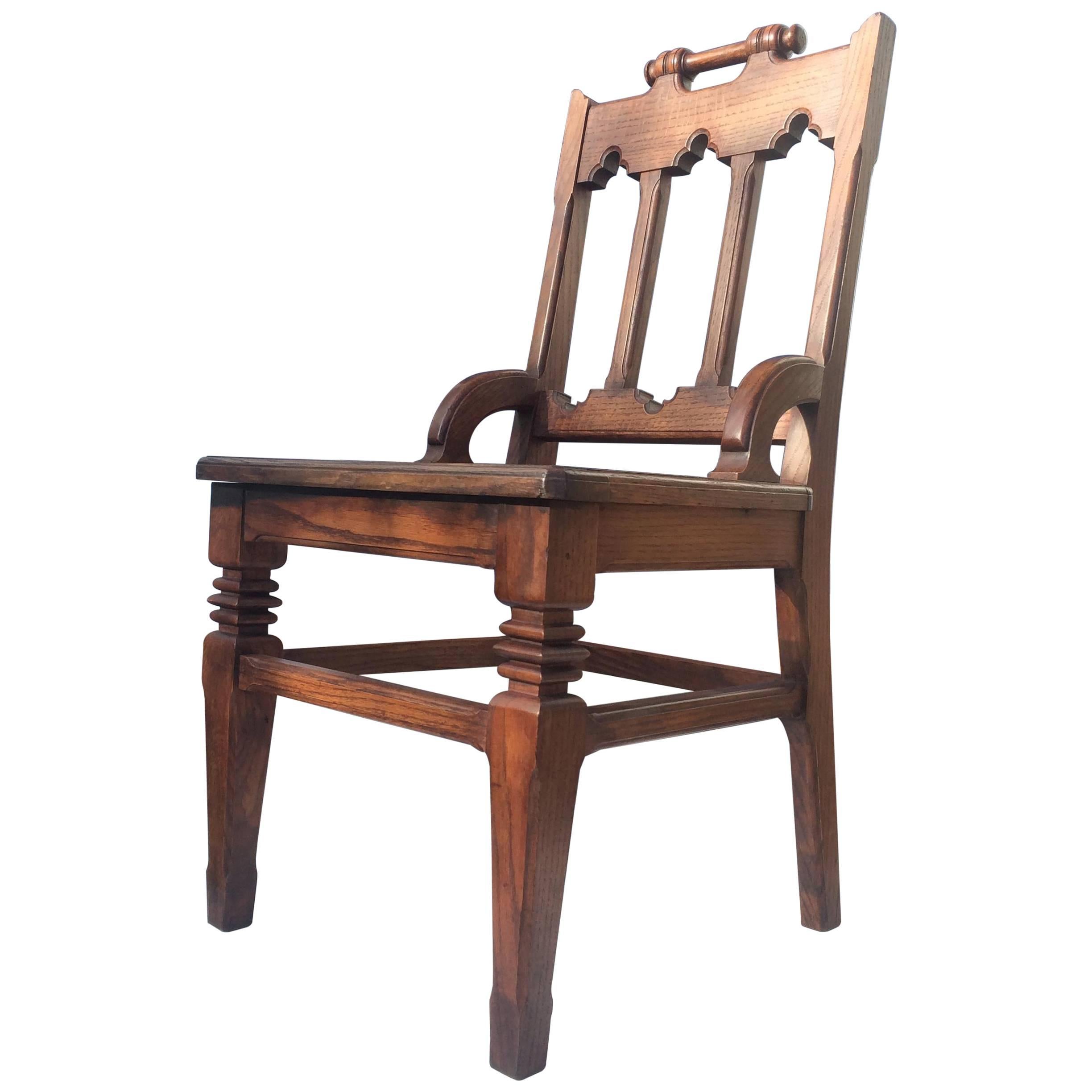 An early 20th Century English oak hall chair with Arts & Crafts and Gothic Style qualities. Handle back, carved graphic front legs. Excellent restored condition. *Requires drop in upholstered seat.