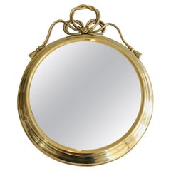 Espejo decorativo ovalado de latón con grandes nódulos en la parte superior
