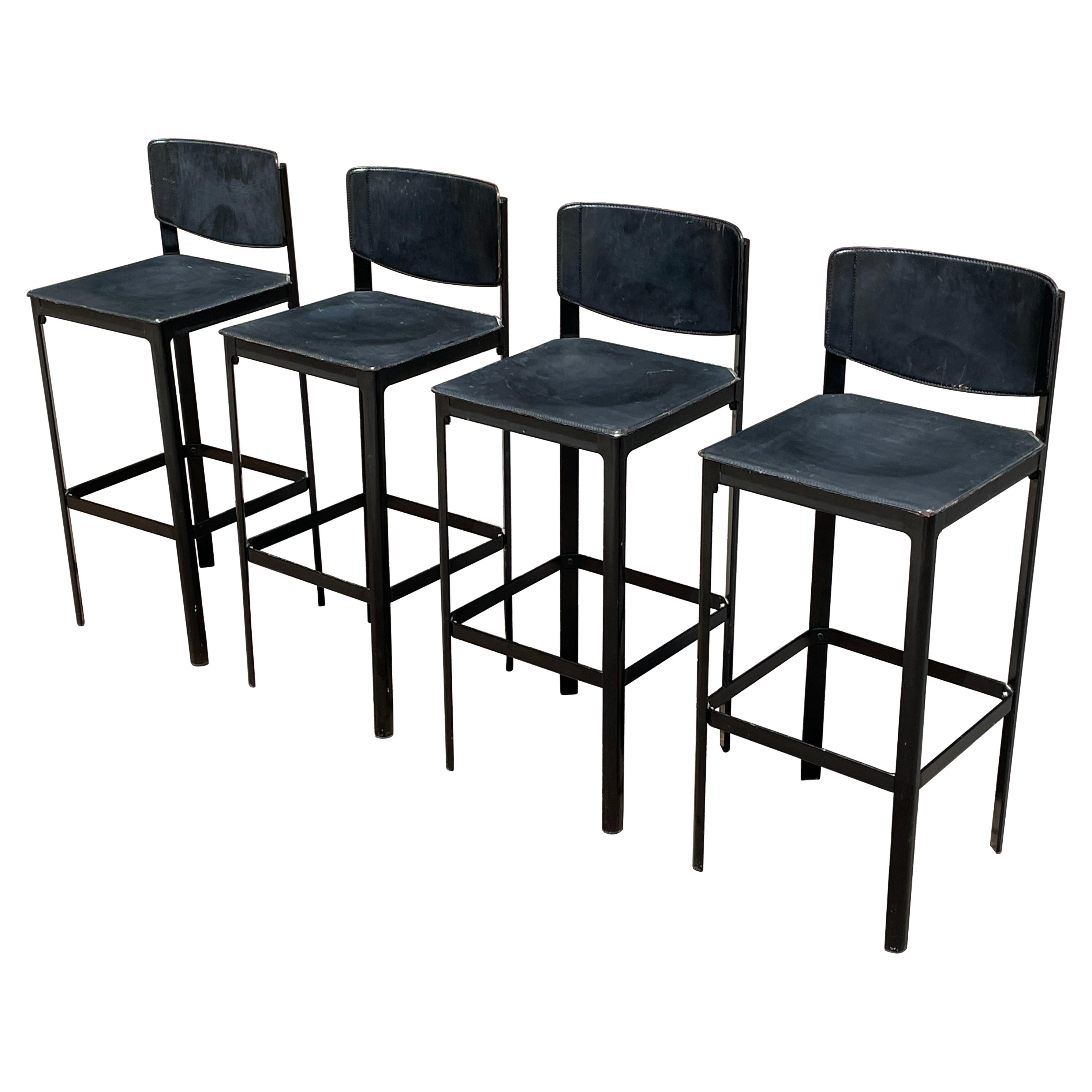 Mid-Century Matteo Grassi black leather bar stools. Italy. c.1980s.

Very cool design features a patinated black saddle leather wrapped atop a steel frame with stitched detailing. A black enameled square metal support bar connects all four legs and