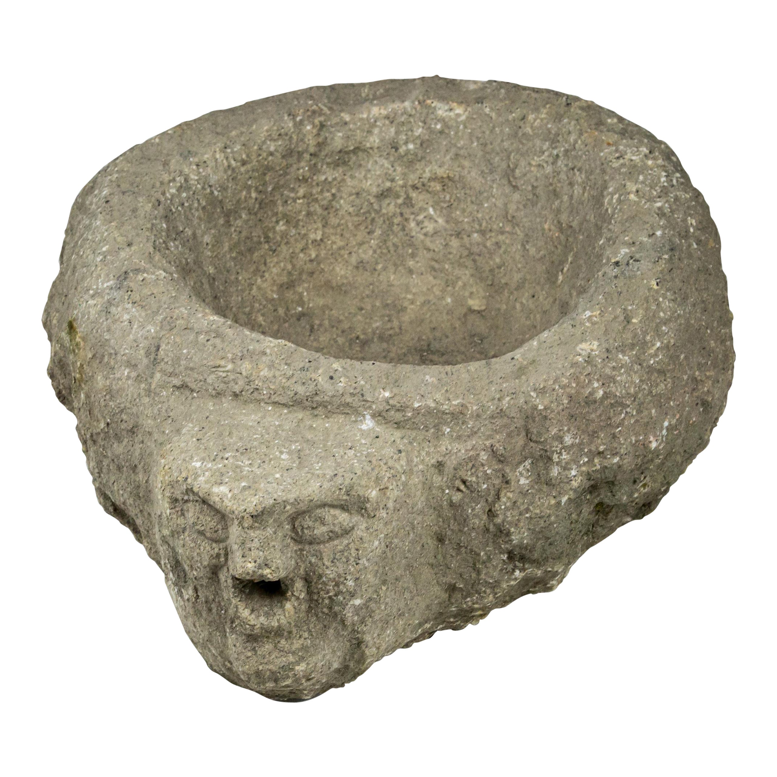 Benitier o acquasantiera in granito tardo medievale con testa primitiva come beccuccio d'acqua