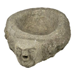 Benitier o acquasantiera in granito tardo medievale con testa primitiva come beccuccio d'acqua