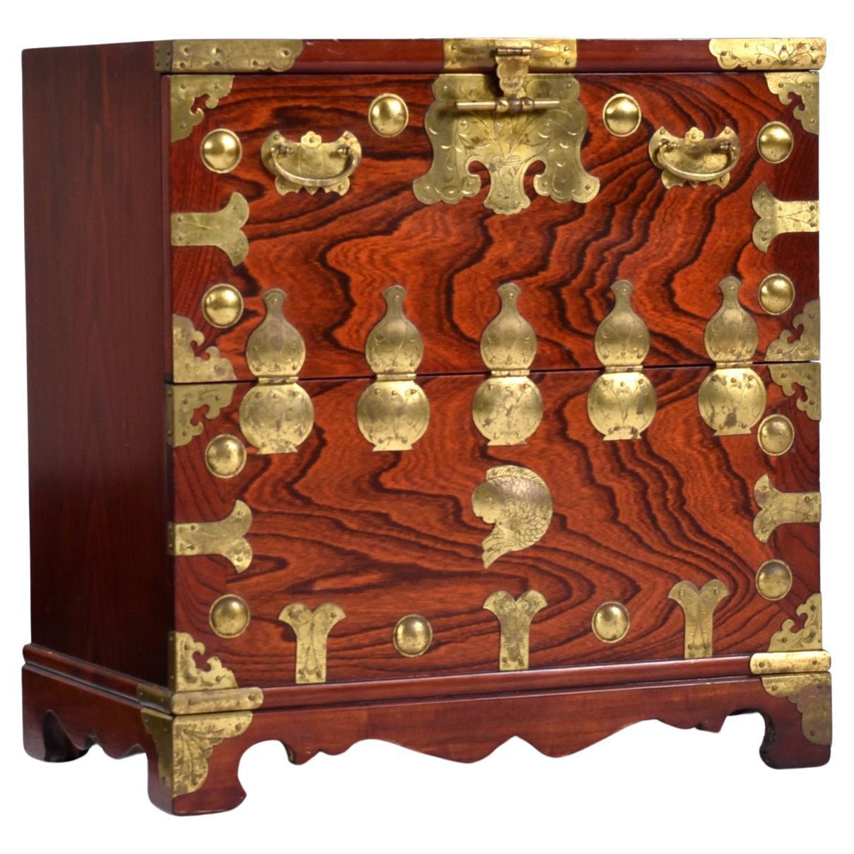 Questa cassapanca asiatica, unica e piccola, è realizzata in legno di palissandro e decorata con ottone coreano. La combinazione tra le venature del palissandro riccamente scolpite e i dettagliati ornamenti in ottone conferiscono a questo piccolo